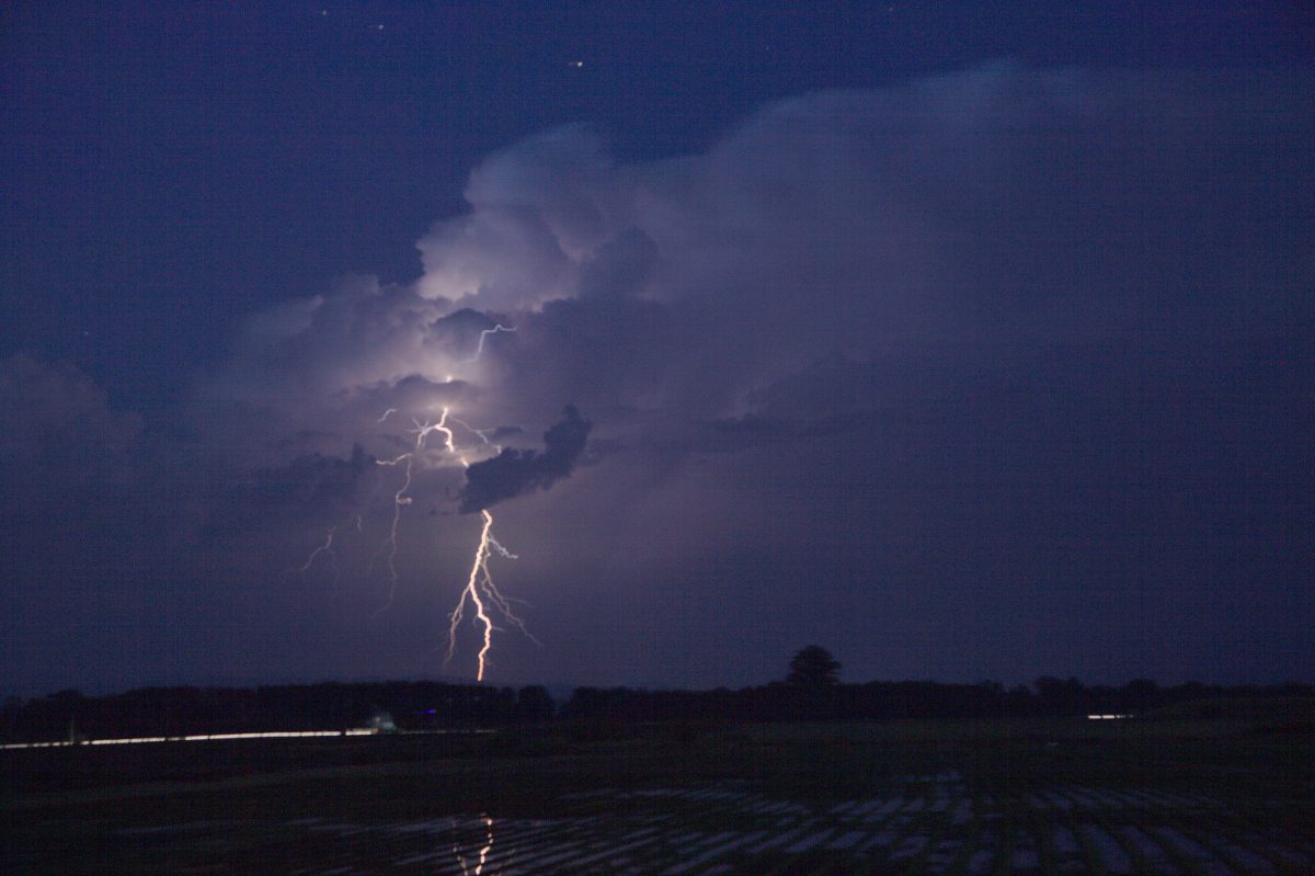 A bright lightning bolt striking from a thunderstorm at night