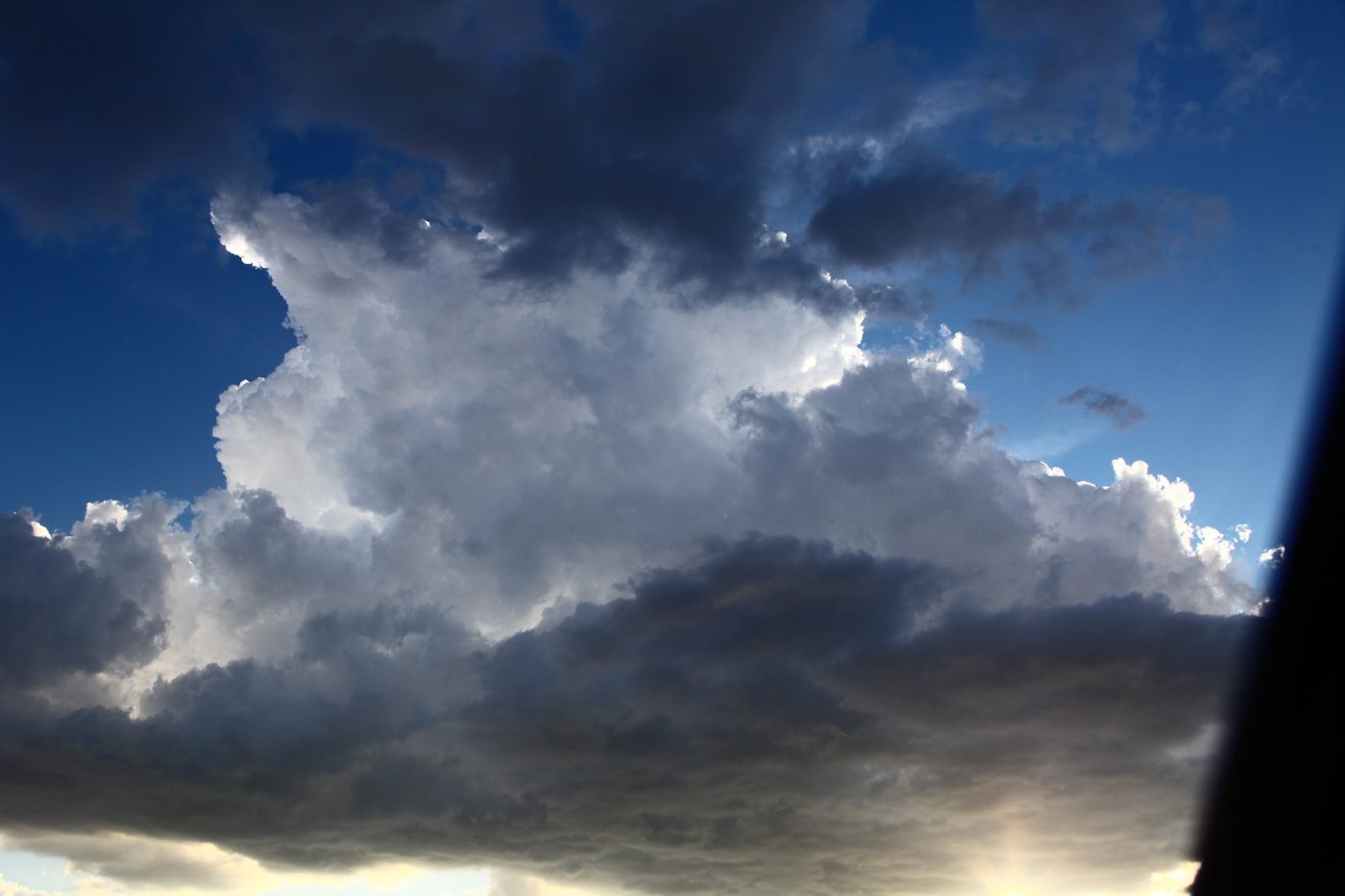 Towering cumulus building into a storm with a dark base and deep blue sky