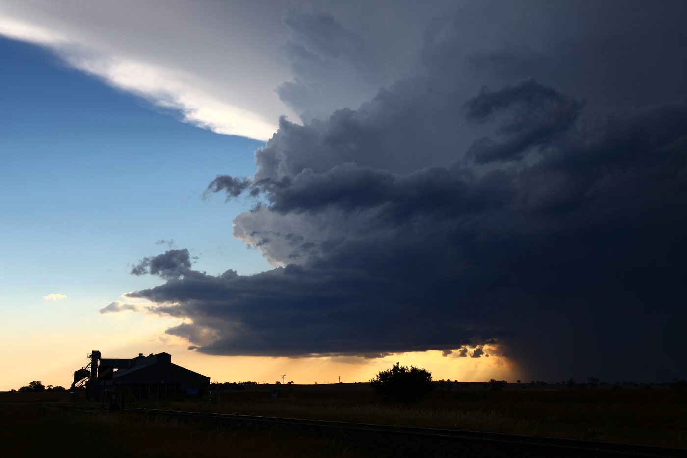 A dark supercell base glowing under golden light on the horizon