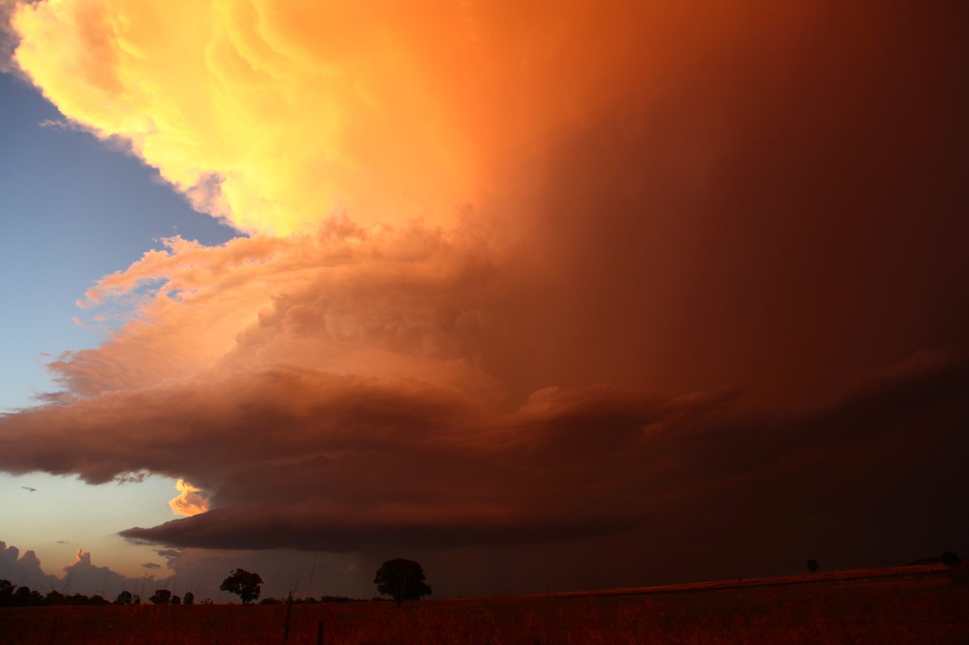 A supercell overhang glowing red and orange at sunset
